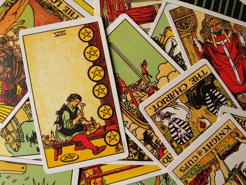 Picture of the Eight of Pentacles tarot card from the original Rider Waite tarot deck with mixed tarot cards in the background