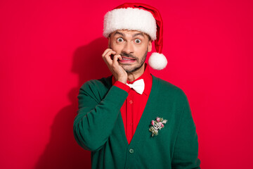 Photo of shocked scared guy dressed xmas green cardigan bowtie biting fingers big eyes isolated red...