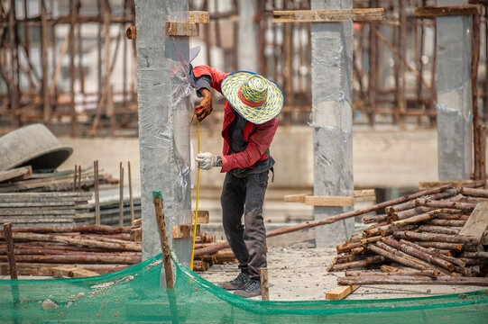 A construction worker, with his tape measure, checks the reference line height which is marked on the concrete column.