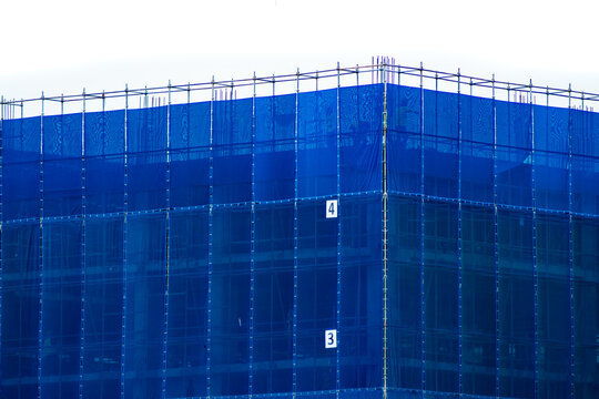 A blue slan surrounds the building under construction.