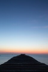 Vertical shot of a long pier in the sea at sunset