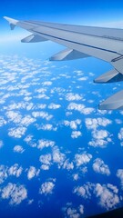 Vertical shot of the wing of an airplane flying over the clouds and the Earth