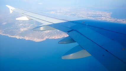 Beautiful view over the wing of an airplane flying over an ocean and the Earth