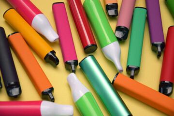 Set of multicolor disposable electronic cigarettes on a bright yellow background.