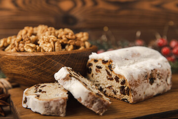 Christmas stollen - traditional German bread on a brown wooden table with fir branches. Festive dessert made of dough, nuts and marzipans sprinkled with powdered sugar.Copy space. Place for text.