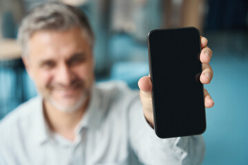 Smiling gray-haired man holds a phone in his hand