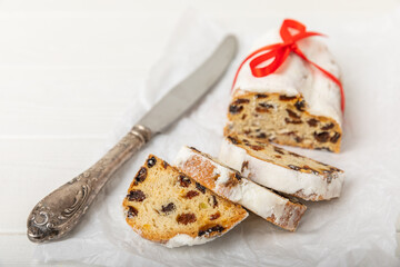 Christmas stollen is a traditional german bread on a white wooden table. Festive dessert made of dough, nuts and marzipans sprinkled with powdered sugar.Copy space. Place for text.