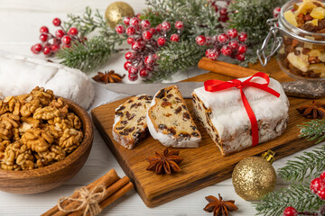 Christmas stollen is a traditional german bread on a white wooden table. Festive dessert made of dough, nuts and marzipans sprinkled with powdered sugar.Copy space. Place for text.