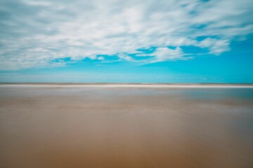Scenic view of a beautiful sandy beach against a blue cloudy sky in Zandvoort - obrazy, fototapety, plakaty
