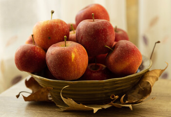 A bowl full of ripe, red apples sits on the kitchen counter and its bright fruit spilling over like a burst of color and the crisp, sweet aroma fills the air, inviting you to reach out and pluck one.