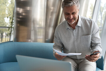 Middle-aged company manager reads business papers with a satisfied look