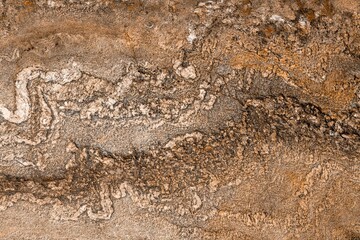 Closeup of a natural stone with white mossy stripes and orange colors