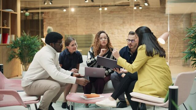 A Group of Multiethnic Enthusiastic Students Comparing Research Findings in University Study Room. Female Doctorate Researcher Joining her Colleagues to Analyze Study Results. Tracking, Wide Shot