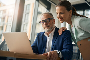 Male and female collegues working with laptop in office