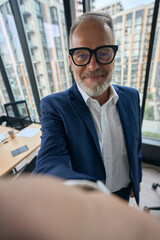 Smiling elegant entrepreneur taking selfie in office