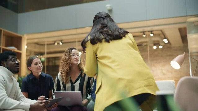 Multiethnic Group of People Brainstorming in a Meeting Room at the Office. Teammates From The Marketing Department Working on a New Campaign Using Laptop and Tablet. Handheld Slow Motion