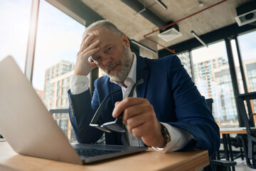 Fototapeta premium Serious mature businessman with laptop in office