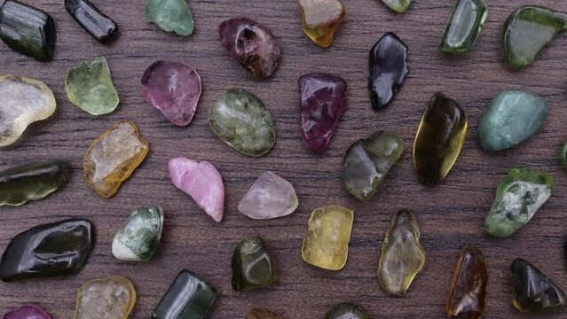 Tourmaline rare jewel stones texture on brown varnished wood background. Moving right seamless loop backdrop.