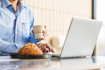 Close-up shot of man using laptop in cafe