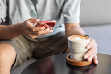 Close-up of a man using a smartphone in a coffee shop.