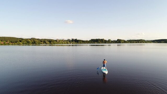 Germany, Bavaria, Allgaeu, standup paddler at the Frankenhofner lake at sunset, drone aerial shot
