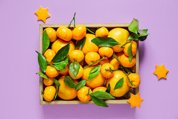 Tangerines with leaves in a box on a lilac background.