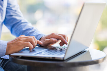 Naklejka na ściany i meble Side view of male businessman hands typing on laptop keyboard.