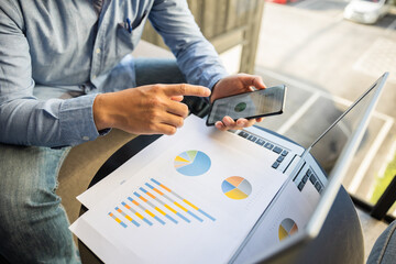 Rear view of male businessman or data analyst vs top view using smartphone and laptop.