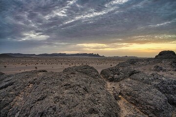 View of a desert landscape under the cloudy sunset sky in Saudi Arabia