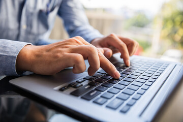 Image of male hands typing on keyboard, selective focus.