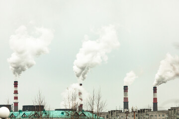 Fototapeta na wymiar industrial chimneys with heavy smoke causing air pollution on the gray smoky sky background 