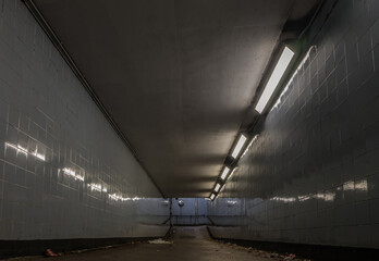 Perspective view of Ambient public underpass with white tiled walls and stripes of ceiling neon...
