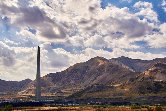 A 1,215 foot high smokestack at a copper smelting plant at the base of the Tooele mountains on a partly cloudy day near the Great Salt Lake, west of Salt Lake City, Utah.