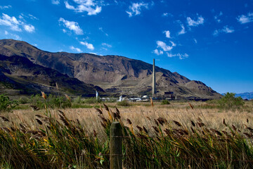 Looking across a field of grass at a copper smelting plant and it's 1,215 foot high smoke stack,...