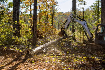 Landscaping work to clear land roots as part of housing development subdivision, using tractors skid steers.