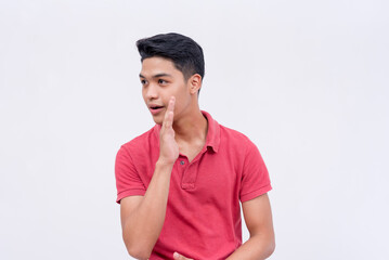 A young man shares a secret confidential story or rumor, whispering while covering his mouth....