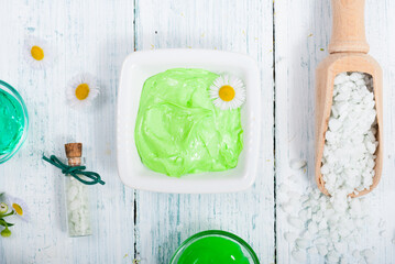 beauty product samples with chamomile flowers on white wooden table