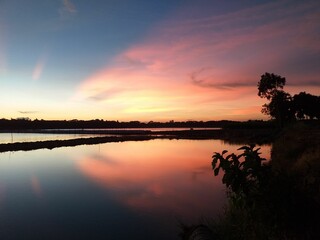 Obraz premium Dramatic scenery of a beautiful sunset in the cloudy sky over the lake in Bangladesh