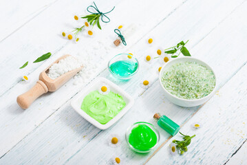 beauty product samples with chamomile flowers on white wooden table