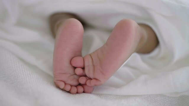Closeup feet of newborn African black baby isolated on white hospital bed sheet. Healthcare and medical love together lifestyle father or mother’s day background concept.