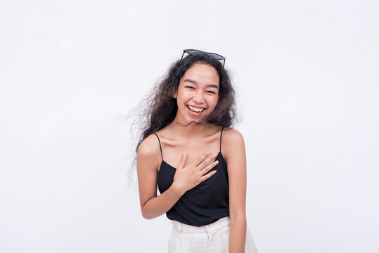 A young asian woman chuckles from a joke. A happy and lighthearted scene. Isolated on a white backdrop.
