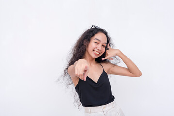 Naklejka premium A confident and carefree young asian woman points to the camera while gesturing to call her sometime. Isolated on a white background.