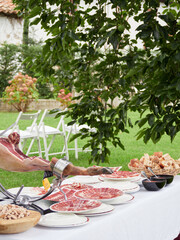 Wedding appetizer table with freshly cut Iberian ham, bread and tomato. Typical Spanish tapas served outside.
