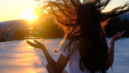 Chica caucásica en la puesta de sol en verano moviendo su pelo