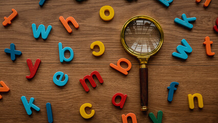 Scattered colorful alphabet with a magnifying glasses. Learning and education concept. Finding...