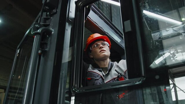 Professional female technician working at machinery equipment production plant connecting wires in tractor