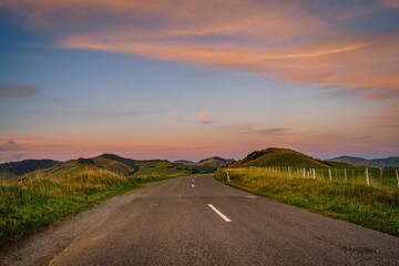 Empty country road against the background of the hills and sky at sunset. Akaroa, New Zealand.