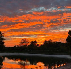 Breathtaking view of dark orange sunset clouds reflected in the lake seen from the promenade