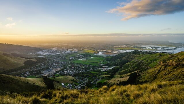 Fototapeta Beautiful view of the town on the green valley at sunset. Christchurch, New Zealand.
