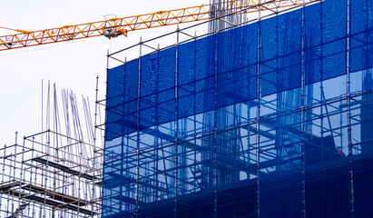 Large construction site including several cranes working on a building complex, with clear blue sky. Construction of new residential high-rise buildings.